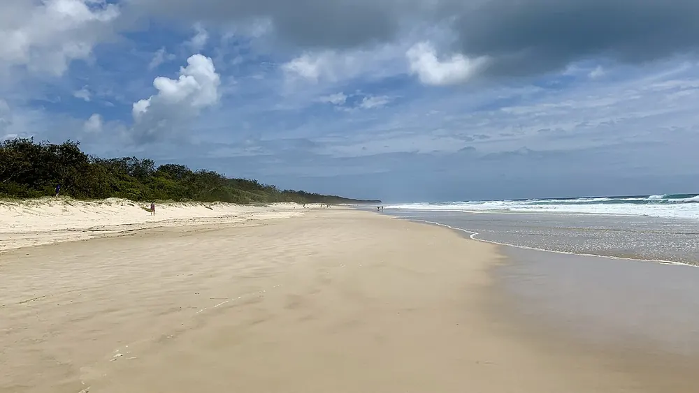 The wide open beach at Casuarina under a cloudy sky