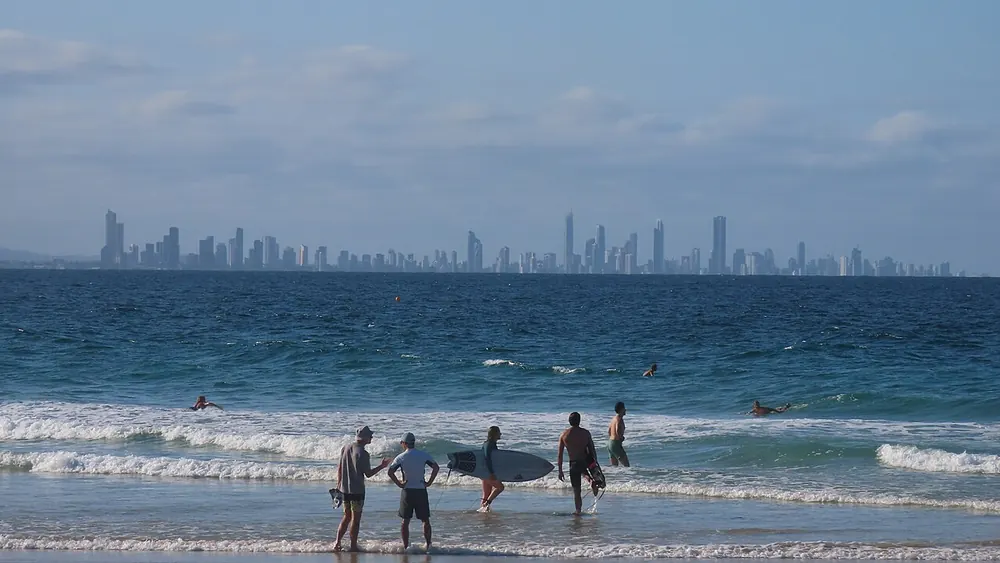 Surfers on Coolangatta Beach with the Gold Coast towers in the distance